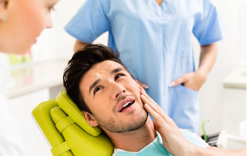 man at dentist holding mouth pain